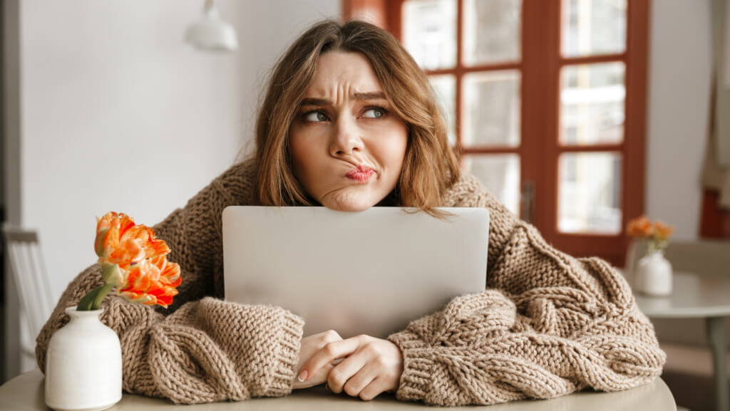Woman looking confused while holding her computer in a sweater