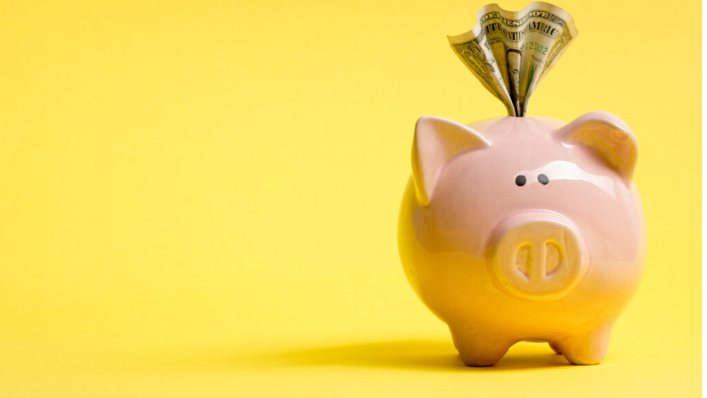 Piggy bank on yellow background with money hanging out of it. For business startups.